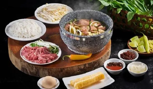 Không chỉ đơn thuần là một tô phở truyền thống, món ăn này gây ấn tượng bởi cách phục vụ đặc biệt với nước dùng đựng trong bát đá nóng, giúp giữ nhiệt lâu và làm chín thịt ngay tại bàn.